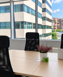 Despacho privado exterior con mesa para cuatro personas, sillas ergonómicas y ventanales con vistas en Cink Coworking Manoteras